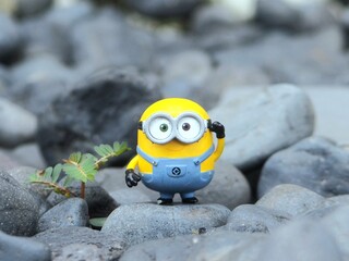 Naklejka premium Indonesia - May 18, 2025 : Mini toy of action figure at outdoor with blurred background. Miniature photography concept design. Minifigure of Minions character from Despicable Me animation film.