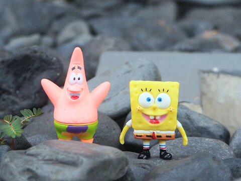 Indonesia - May 18, 2025 : Mini toy of action figure at outdoor with blurred background. Miniature photography concept design. Minifigure of Spongebob Squarepants and Patrick Star character from film.