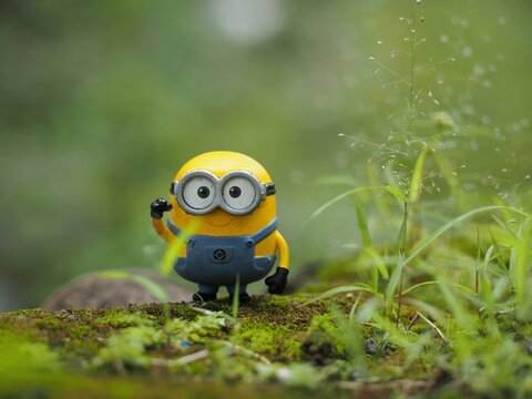Indonesia - February 14, 2023 : Mini toy of action figure at grassland with blurred background. Toy photography concept. Minion character at outdoor with green grass conceptual design.