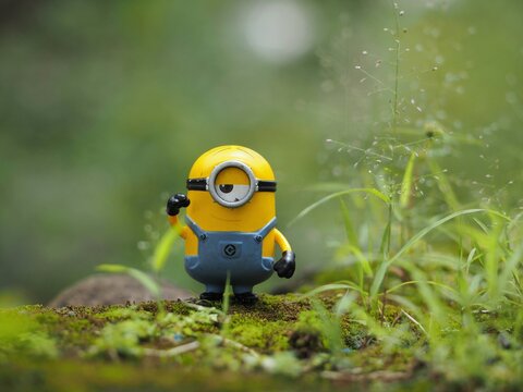 Indonesia - February 14, 2023 : Mini toy of action figure at grassland with blurred background. Toy photography concept. Minion character at outdoor with green grass conceptual design.