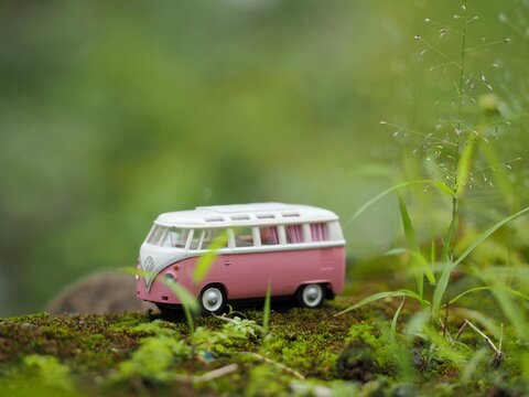 Indonesia - February 3, 2023 : Mini toy of action figure at outdoor with blurred background. Toy photography concept design. Car toy of VW combi with roof rack at park. Roadtrip with campervan.