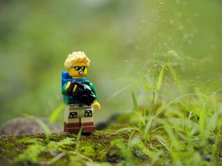 Fototapeta premium Indonesia - February 14, 2023 : Mini toy of action figure at grassland with blurred background. Toy photography concept. Adventure man concept design.