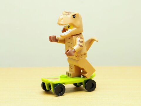 Indonesia - February 10, 2026 : Mini toy of action figure at outdoor with blur background. Miniature photography concept design. Minifigure of Tyrannosauros Rex character playing skate board at arena.