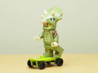 Fototapeta premium Indonesia - February 10, 2026 : Mini toy of action figure at outdoor with blur background. Miniature photography concept design. Minifigure of Triceratops character playing skate board at sport arena.