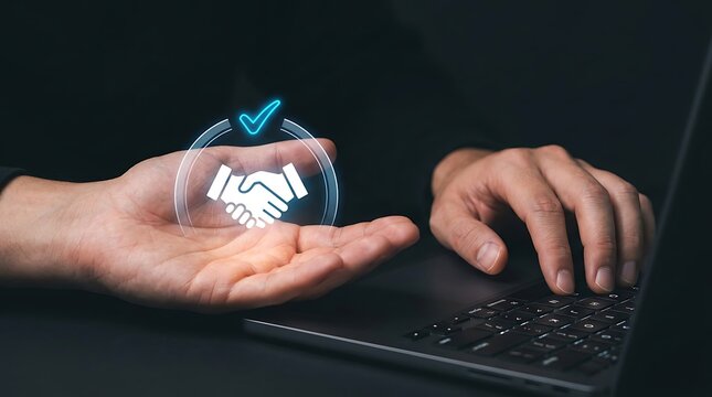Hand holding digital handshake hologram. Business agreement icon on laptop screen.