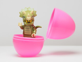 Fototapeta premium Indonesia - February 8, 2026 : Mini toy of action figure at outdoor with blurred background. Miniature photography design. Minifigure of Triceratops dino character coming out from egg. New born concep