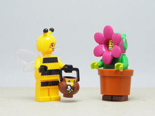 Fototapeta premium Indonesia - January 5, 2026 : Mini toy of action figure at table with blurred background. Miniature photography concept design. Minifigure of Flower and Yellow Bee character at garden.