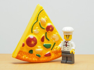Fototapeta premium Indonesia - January 4, 2026 : Mini toy of action figure at outdoor with blurred background. Miniature photography concept design. Minifigure of Young Chef character with Pizza, Pan and food truck.