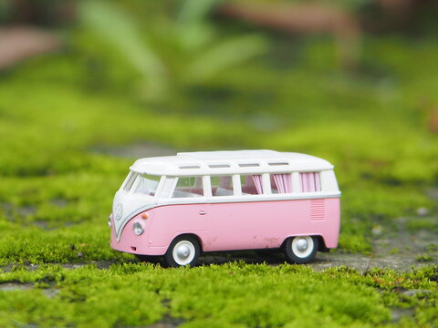 Indonesia - January 4, 2026 : Mini toy of action figure at outdoor with blurred background. Miniature photography concept design. Car toy of VW combi with roof rack at park. Roadtrip with campervan.