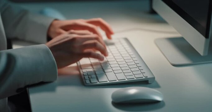 Professional person typing on computer keyboard at office desk in evening