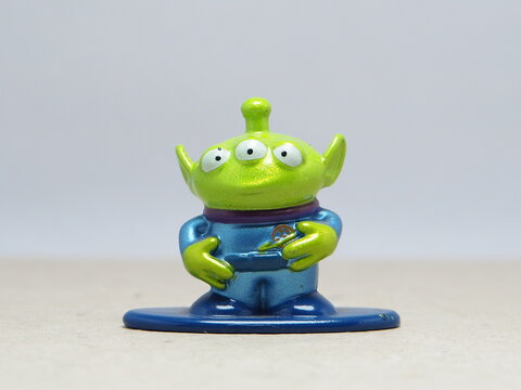 Indonesia - November 27, 2025 : Mini toy of action figure at table with blur background. Miniature photography concept design. Minifigure of Woody, Buzz Lightyear and Green Alien character from film.