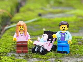 Fototapeta premium Indonesia - November 23, 2025 : Mini toy of action figure at table with blurred background. Miniature diorama photography concept design. Minifigure of Mother, Father and baby character with stroller.