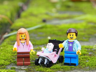 Fototapeta premium Indonesia - November 23, 2025 : Mini toy of action figure at table with blurred background. Miniature diorama photography concept design. Minifigure of Mother, Father and baby character with stroller.