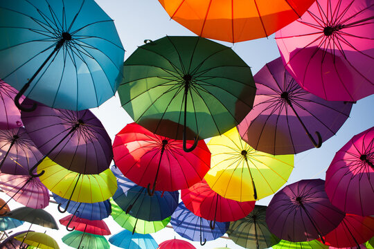 Bright umbrellas floating overhead in a colorful outdoor arrangement, vibrant decorative display, creative background, summer festival.