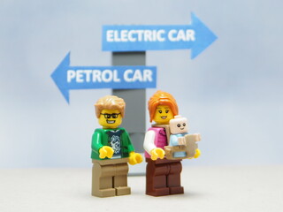 Fototapeta premium Indonesia - April 14, 2025 : Mini toy of action figure at table with blurred background. Business photography concept design. Minifigure of people character with roadsign. Electrical Car vs Petrol Car