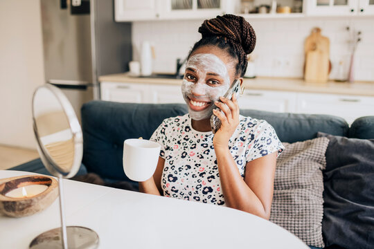 Joyful african american woman with a face mask talking on a phone