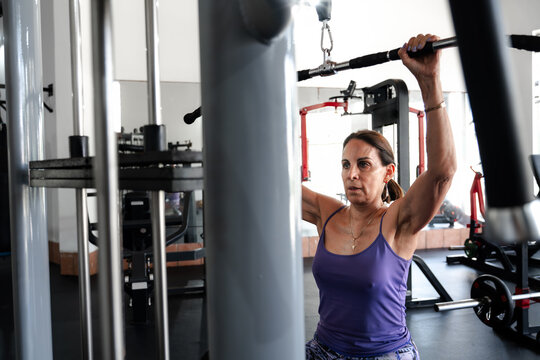 Mature Woman Training on Weight Machine at Gym