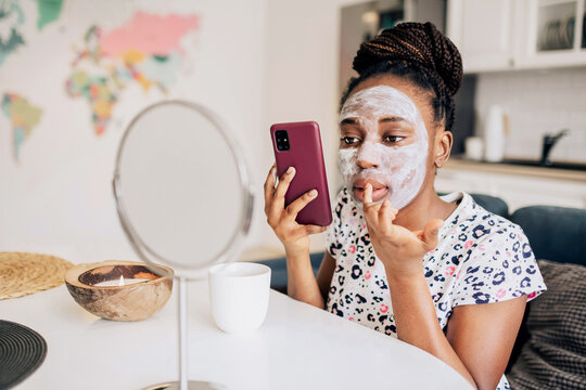 Portrait of african american woman with a face mask holding a phone