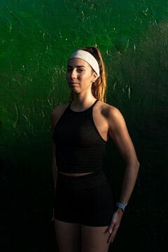 Resolute woman standing by a textured green wall 