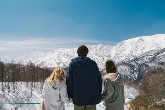 Father with girls are looking at the snowy mountains
