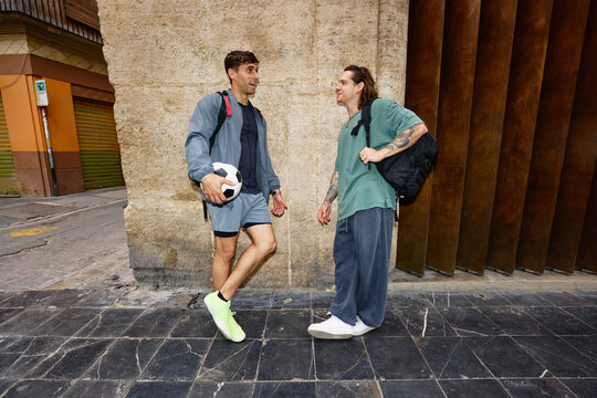 Two young men prepare for a soccer game on a city street