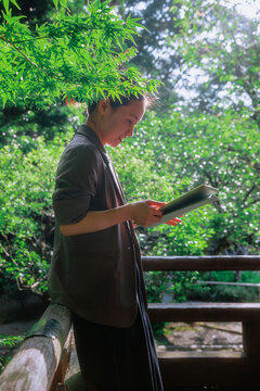 A professional woman focusing on digital tablet work outdoors.