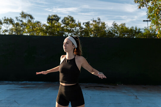 Athletic woman breathing deeply with arms open on a court