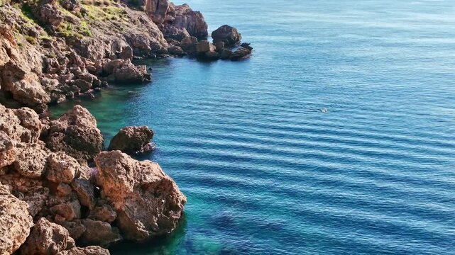 Rugged limestone cliffs rise above vivid turquoise sea water along rocky antalya coastline.