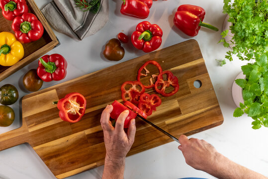 Crop chef cutting paprika for salad