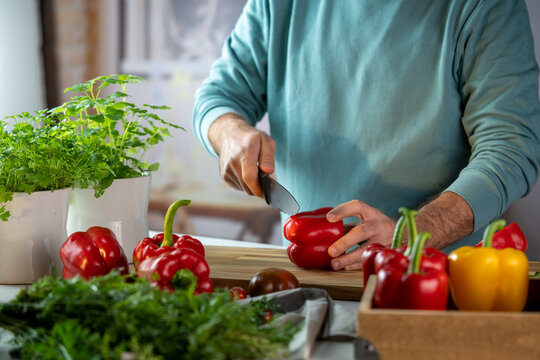 Crop chef cutting paprika on chopping board