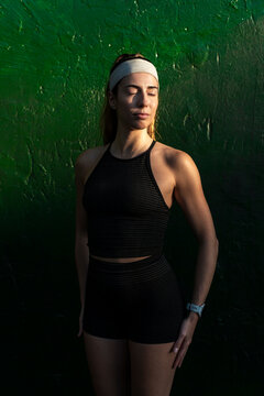 Serene athlete pausing by textured green wall