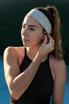 Woman inserting a wireless earphone before workout