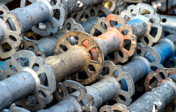 Stacked galvanized scaffold standards with rosette discs used as structural components of a modular scaffolding system.