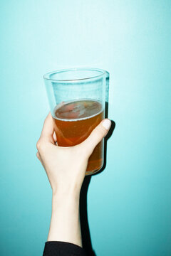 Hand holding drinking stein full of drink on coloured background
