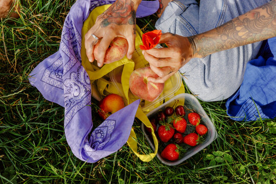 Person sitting on grass preparing fresh fruits in a park