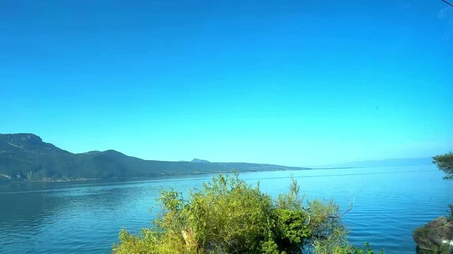 Scenic view from a moving train revealing a breathtaking mountain landscape over lake geneva with morning fog lifting from the calm blue water on a beautiful sunny day