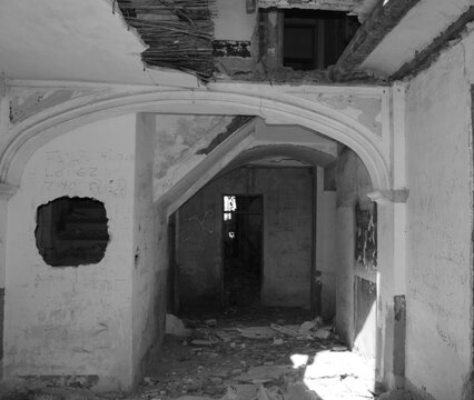Interior de casa abandonada y en ruinas, paredes da&ntilde;adas por el tiempo y techos derrumbados en blanco y negro
