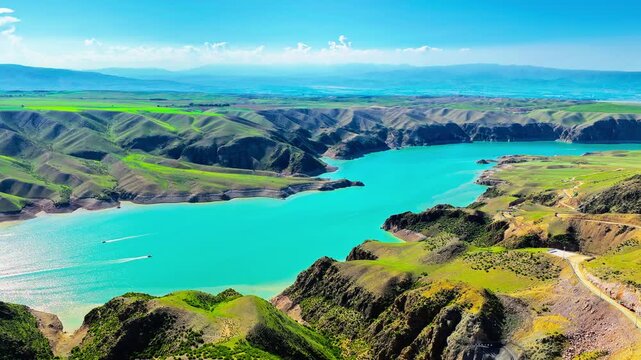 High angle view of Kuoksu Grand Canyon featuring a turquoise river winding through lush green hills and rugged mountains in Xinjiang, China.