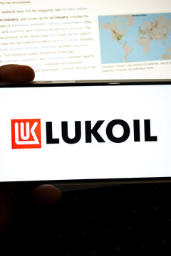 Hand holding device displaying lukoil branding with petroleum industry text