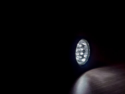 Flashlight beam shining in a dark room, creating a focused light spot and strong contrast, highlighting visibility, direction, and minimal illumination in a low-light environment.