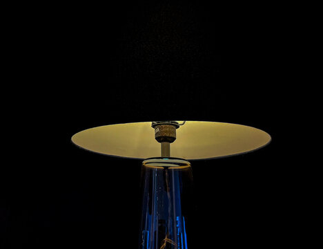 Modern table lamp glowing against a dark background, creating a warm minimalist atmosphere with elegant lighting, clean composition, and dramatic contrast for interior design concepts.
