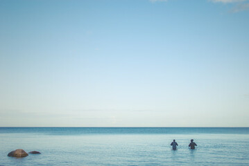 Fototapeta premium Two fishermen standing in the sea water, Marielyst, Denmark