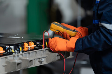 Naklejka na ściany i meble High-voltage battery checks, and maintenance. Technician or Mechanic wearing protective gloves diagnosing electric car vehicles battery, component checks at auto workshop