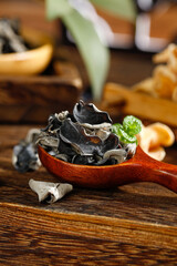 Dried Black Fungus Mushrooms in Wooden Spoon - Asian Cooking Ingredient on Rustic Kitchen Table © DoThi
