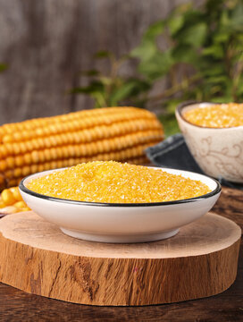 Yellow Corn Grits and Cornmeal in Bowls with Fresh Corn Cobs on Wooden Cutting Board