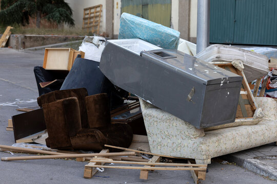 Bulky waste and old furniture illegally dumped on a city street pavement