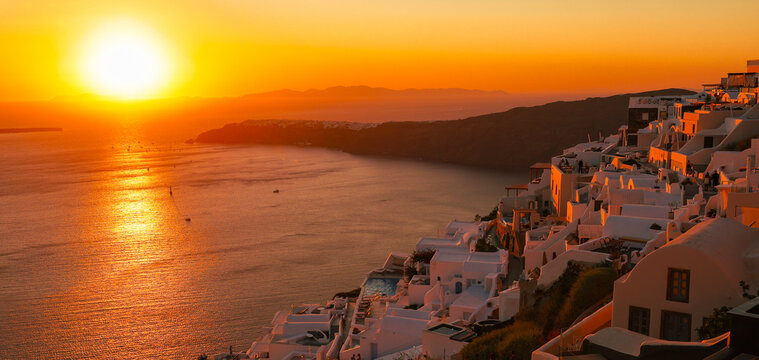 The sun sets over Santorini&rsquo;s caldera, bathing whitewashed villages in golden light and reflecting across the tranquil Aegean Sea.