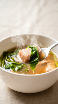 Close up macro of steaming Sinigang na baboy on spoon.