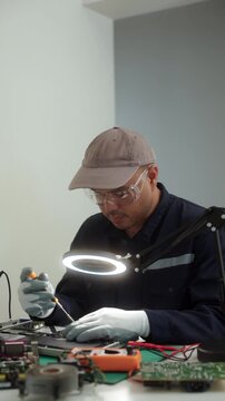 Electronics technician repairing a printed circuit board in a modern repair lab. PCB diagnostics, soldering electronic maintenance, right to repair. Sustainable technology and skilled technician.
