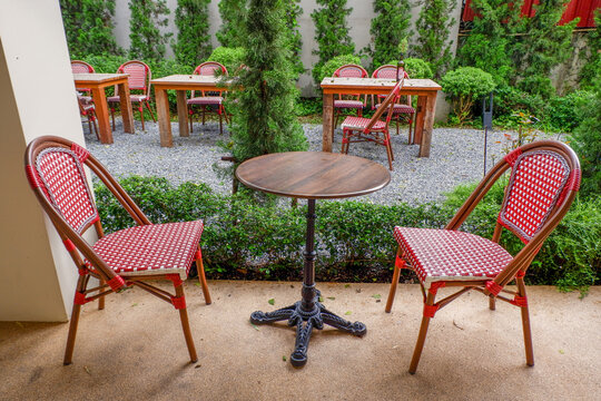 Luxury chair and wooden table set in english garden on a sunny day,outdoor seating for restaurant or cafe,Near paver patio with sitting area and small garden in forest.